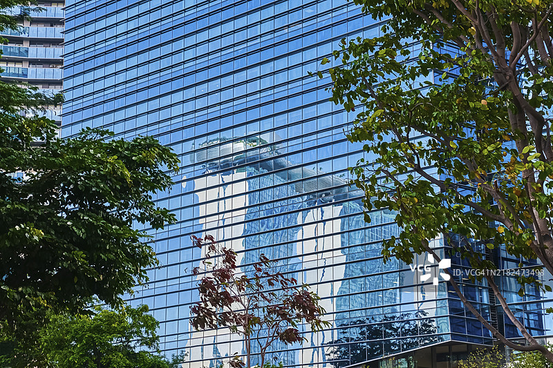 滨海湾金沙的倒影，酒店、赌场、会议中心，位于新加坡滨海湾的高层建筑玻璃墙上。阳光洒下，绿树成荫。著名的旅游目的地，必看地标。标志性的未来主义建筑，象征。图片素材