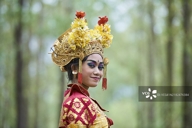 年轻的巴厘岛乐工舞者在树木成行的乡村道路上站立的肖像图片素材