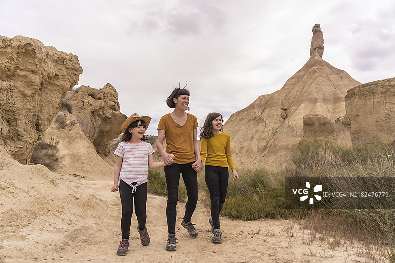 母亲和女儿们在沙漠中一起散步的横向照片，留有空白区域。图片素材