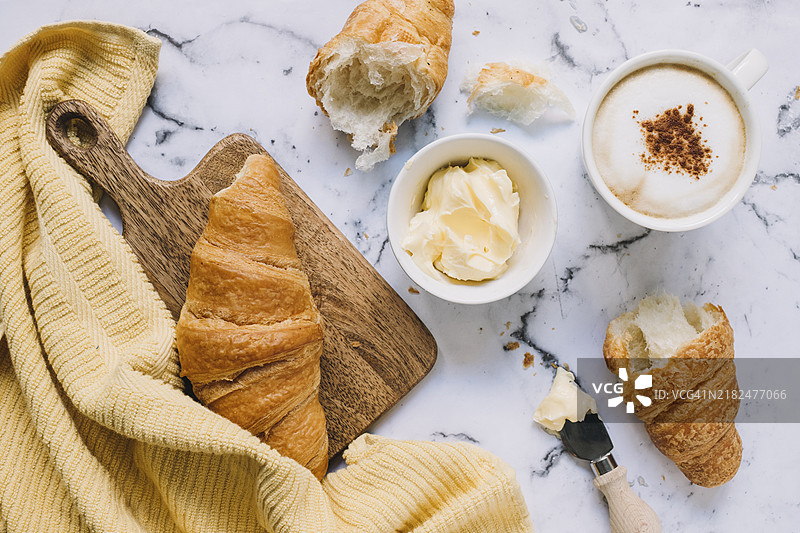 黄餐巾上的黄油可颂和咖啡杯，搭配大理石桌面图片素材