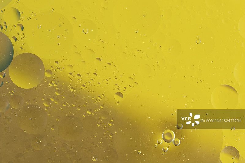 宏观特写：油与水混合，背景为黄色图片素材