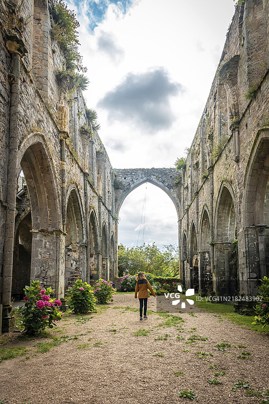 一位年轻女性正在法国布列塔尼的帕伊蒙村参观博波特修道院教堂的遗址。图片素材