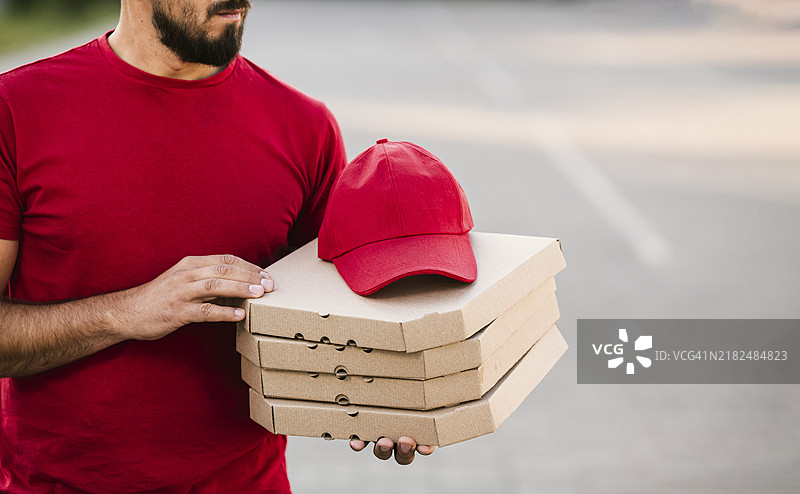 快递员手持披萨盒的特写镜头图片素材
