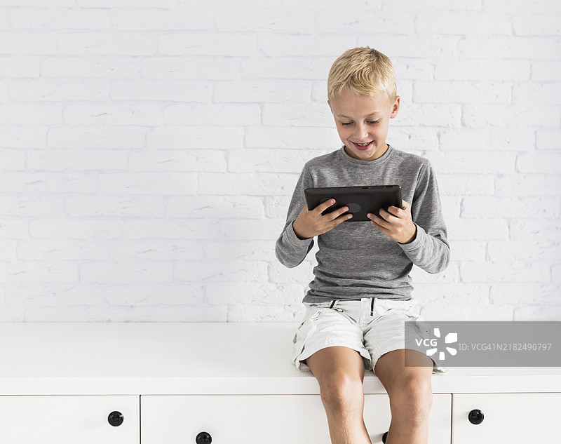 可爱的小男孩在玩平板电脑。图片素材