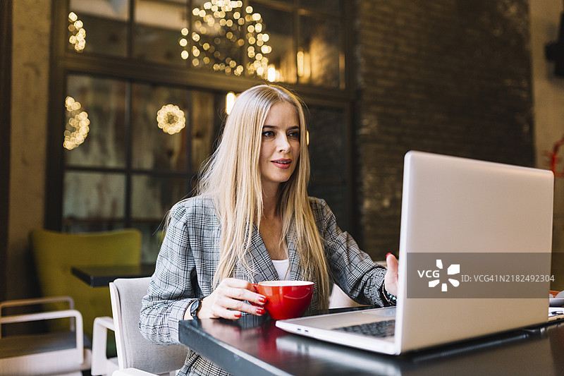 时尚的女商人在舒适的咖啡店里使用笔记本电脑图片素材