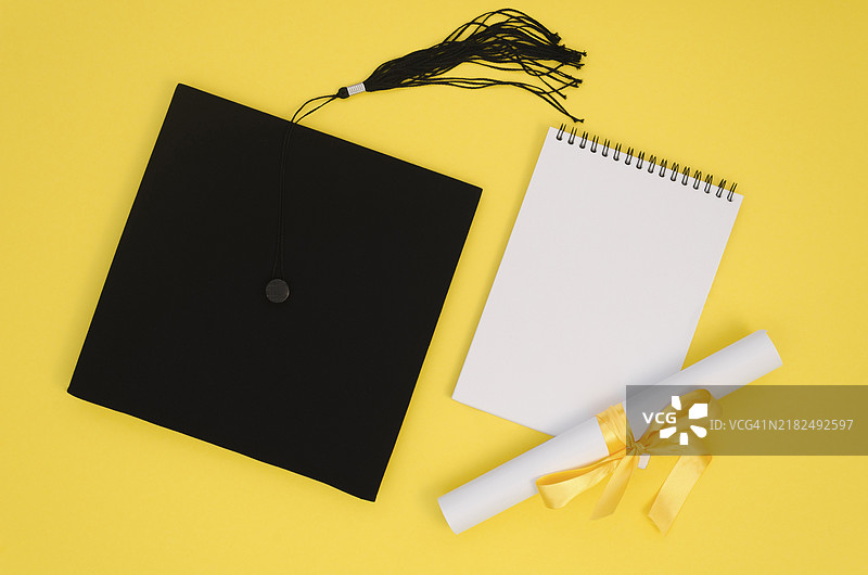 平铺的节日毕业布置，旁边有一本空白笔记本图片素材