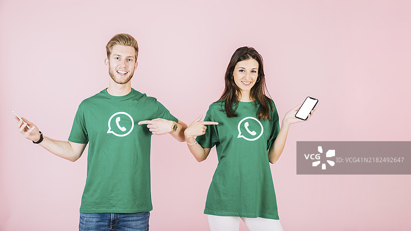 一对情侣用手机指着他们的T恤，上面有WhatsApp图标图片素材