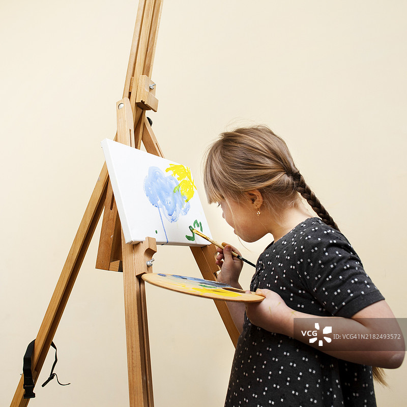 侧面视角的唐氏综合症女孩正在用画笔作画图片素材