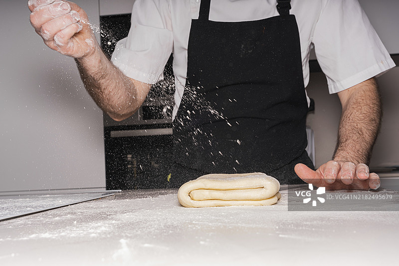 糕点师在家制作自制可颂，准备酥皮面团并添加面粉。图片素材