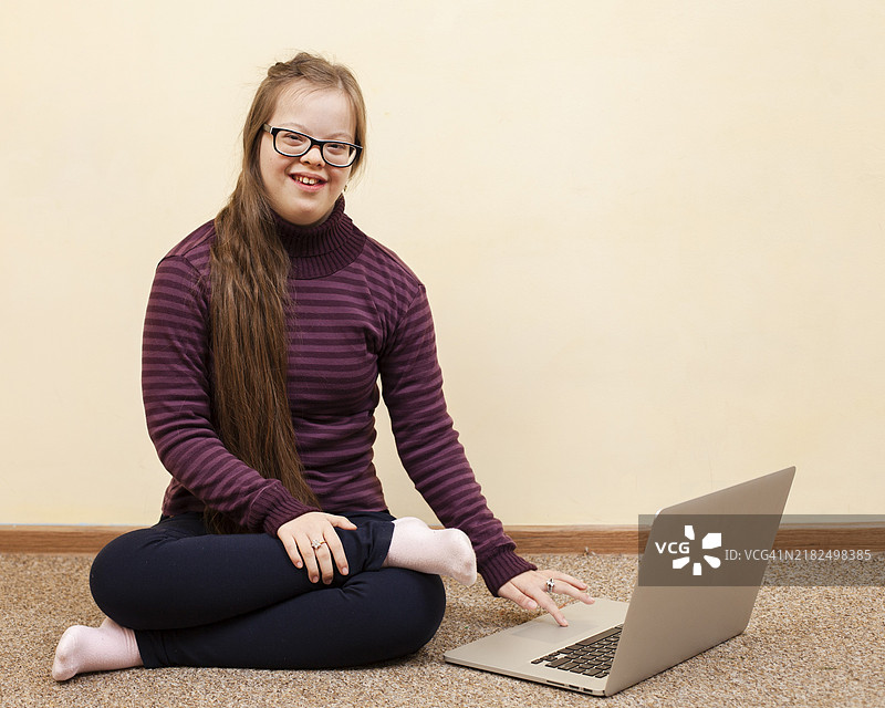 正面微笑的唐氏综合症女孩与笔记本电脑图片素材
