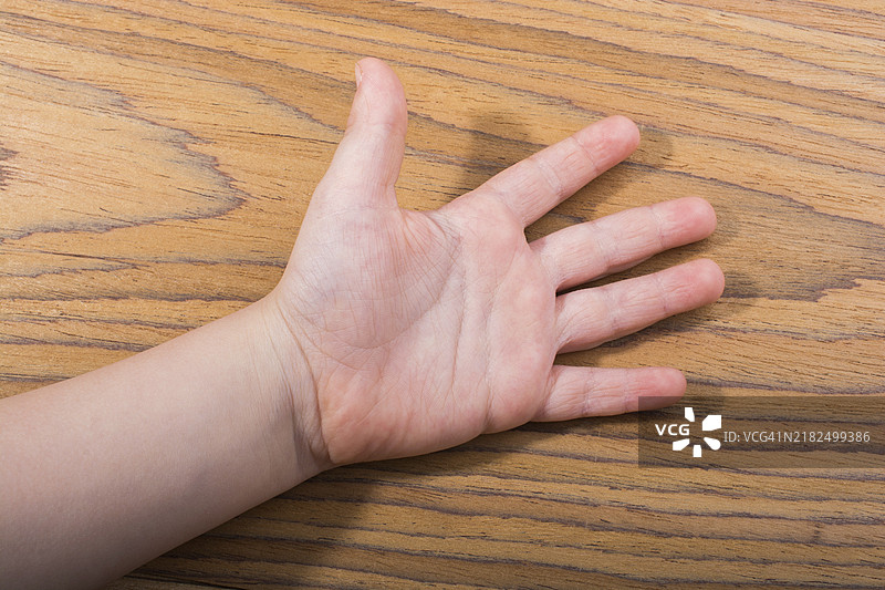 幼儿的手掌张开，五个手指放在木质纹理上图片素材