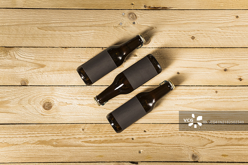 三瓶啤酒的高角度视图，背景为木质纹理图片素材