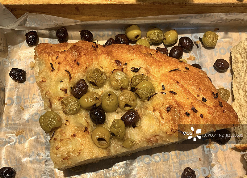 新鲜出炉的手工有机佛卡夏，配有绿橄榄、黑橄榄和香草，展示在2024年3月的意大利市场摊位上图片素材