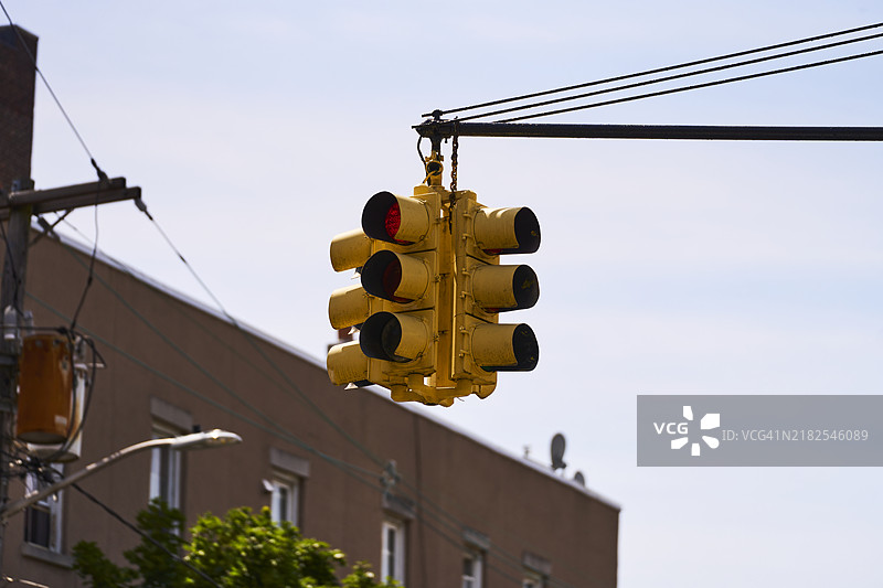纽约市街道上低角度侧视的黄色交通信号灯，背景是天空。图片素材