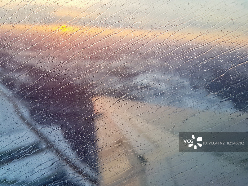 黎明时分雨水覆盖的飞机窗户与机翼视角图片素材