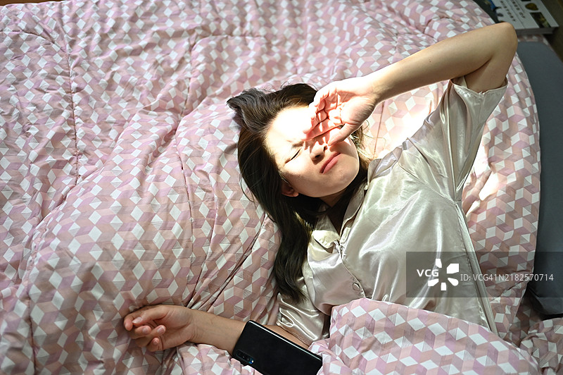 女人在早晨醒来，阳光洒在她的脸上。图片素材