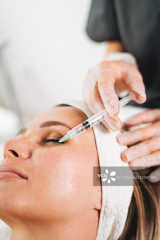 年轻女性在美容院的沙发上接受面部美容注射图片素材