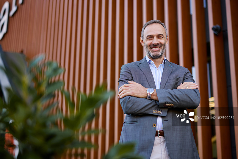 自信的商人在户外双臂交叉站立图片素材