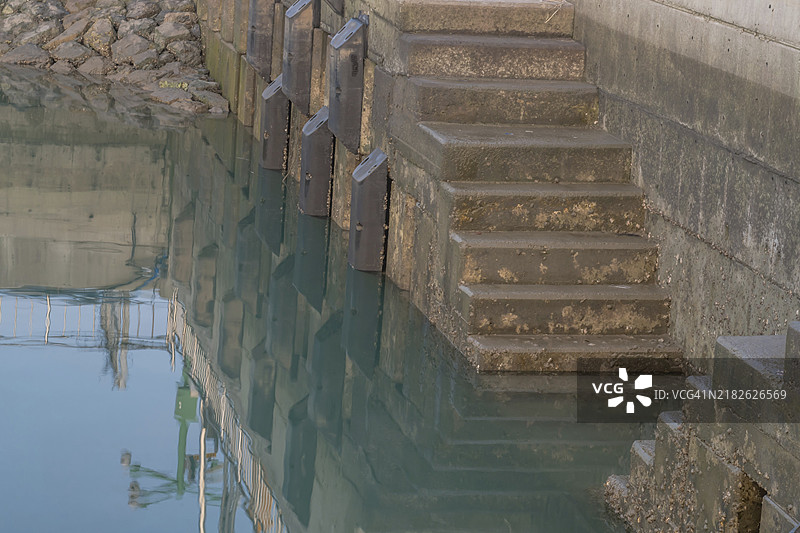 海洋钓鱼码头的混凝土楼梯和墙壁，水中倒影清晰可见图片素材