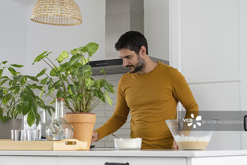 年轻男子在家里的厨房里制作自制面包图片素材