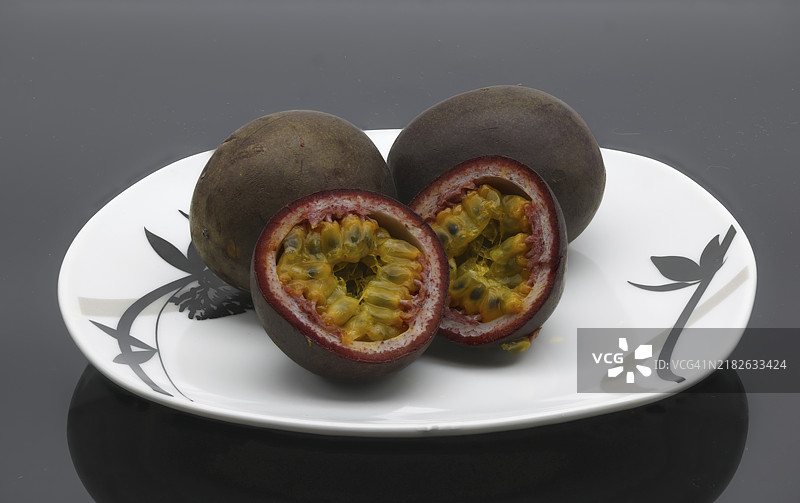 整颗和切片的百香果（Passiflora edulis）放在盘子上图片素材