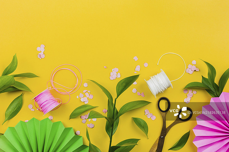 纸花彩屑、绿叶、线轴，黄色背景图片素材