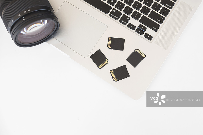 高角度视图的单反相机、存储卡和笔记本电脑键盘图片素材