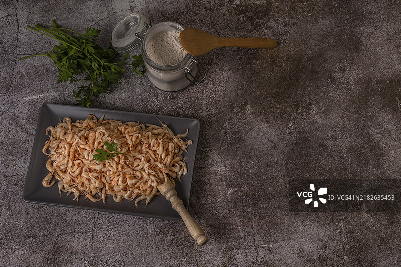 新鲜虾放在陶瓷托盘中，旁边有香菜、面粉和洋葱图片素材