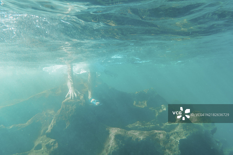 一位年轻的白人棕发女孩穿着人字拖走入水中，水下影像，夏季生活方式图片素材