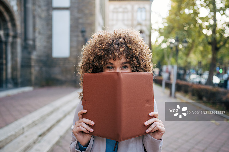 一名快乐的男学生站在大学外面。图片素材