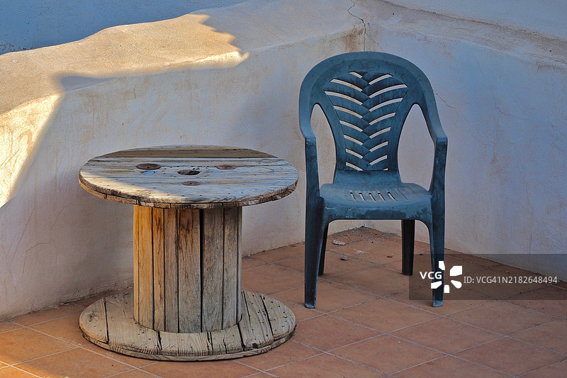 安达卢西亚魅力，极简主义，带电缆卷的椅子，木质电缆卷制成的桌子，蓝色塑料椅子图片素材