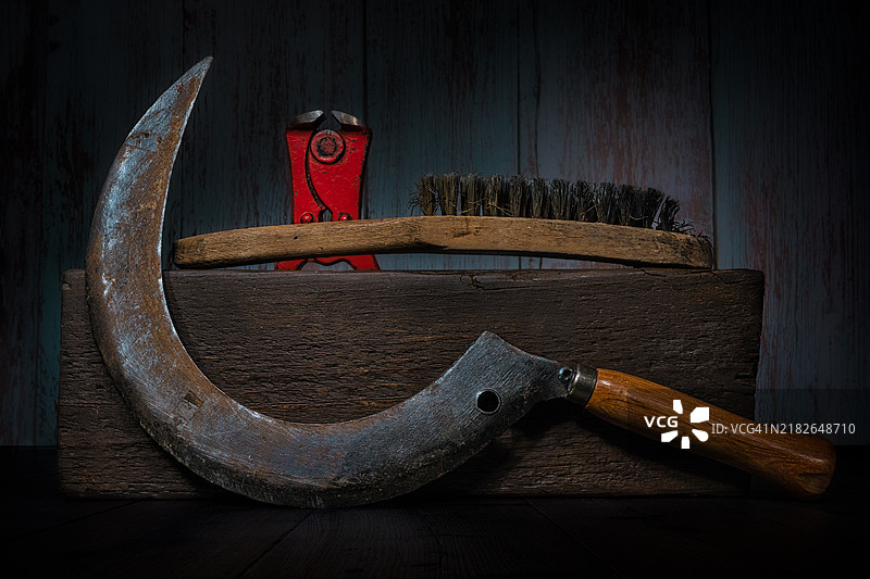 木块上的镰刀、钢丝刷和钳子的静物画图片素材