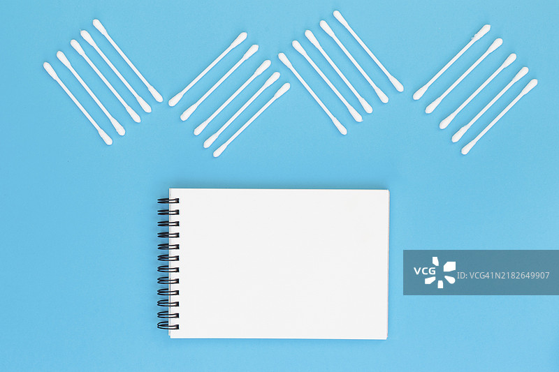 用棉签制作的设计，空白螺旋笔记本，蓝色背景图片素材