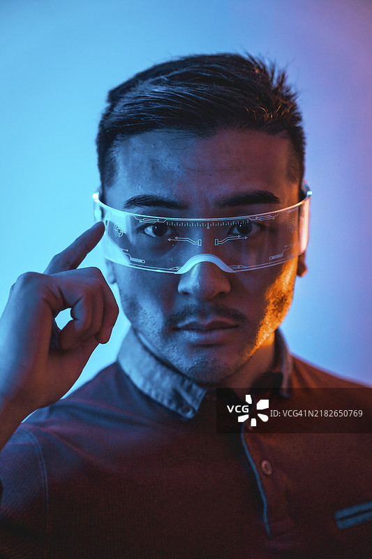 佩戴霓虹眼镜的中国男性肖像，蓝色和橙色光线，未来主义概念，赛博人类技术图片素材