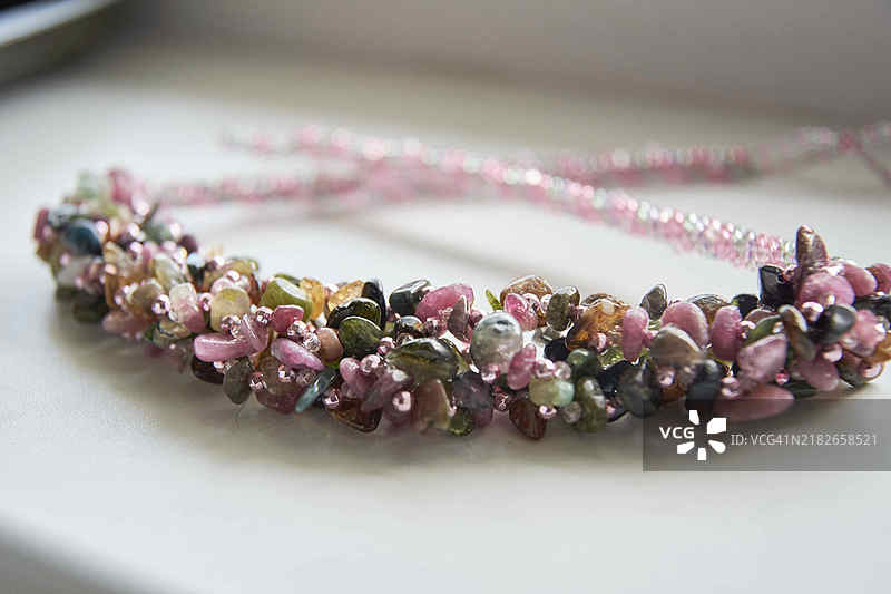 手工制作的珠子和不同颜色的石头项链，摆放在白色桌子上的DIY珠宝装饰图片素材