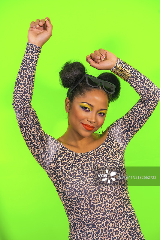 一位惊讶的女性特写肖像，妆容鲜艳，扎着两个侧发髻，手中拿着时尚太阳镜。图片素材