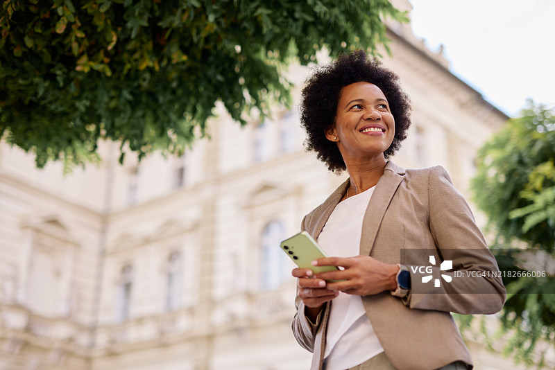自信的女商人在城市环境中户外拿着智能手机图片素材