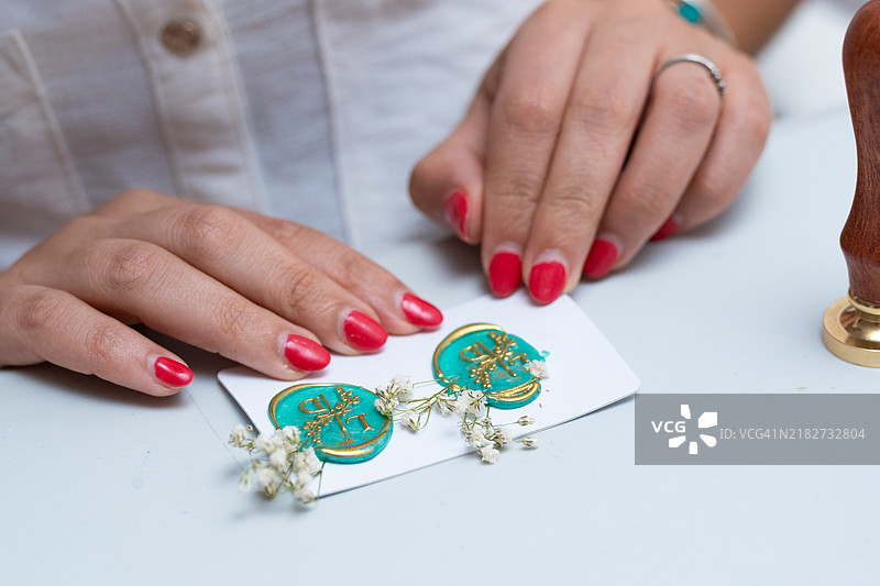 女人在带有花卉装饰的婚礼邀请函上盖蜡封图片素材