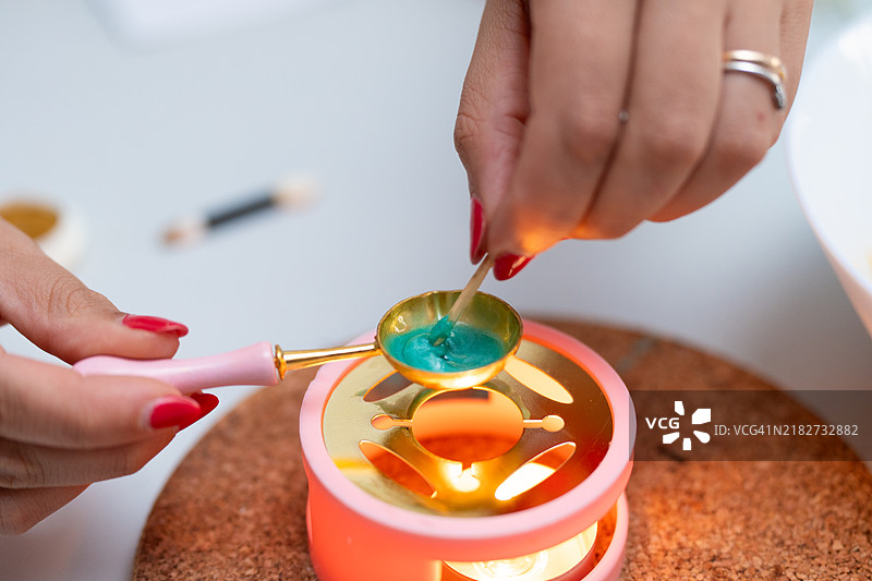 女性正在融化绿色蜡以封印婚礼邀请函信封图片素材