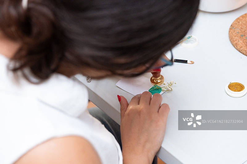 女性使用封蜡和印章制作婚礼请柬图片素材