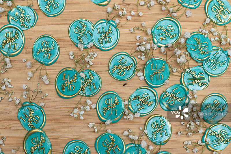 带有金箔装饰的绿松石色蜡封，配以满天星花，适用于婚礼请柬图片素材