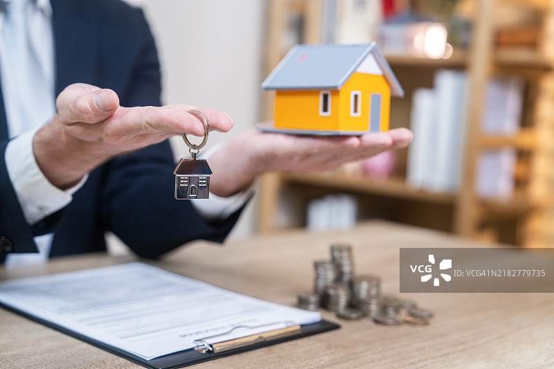 房地产经纪人手持钥匙和小房子模型图片素材