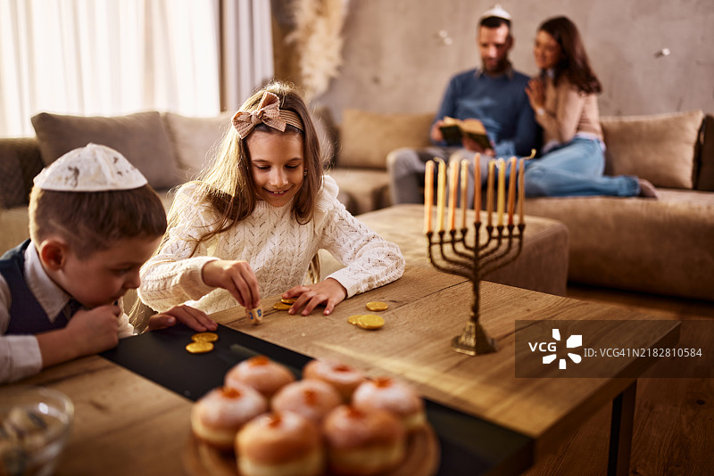 快乐的孩子们在家里玩陀螺庆祝光明节。图片素材