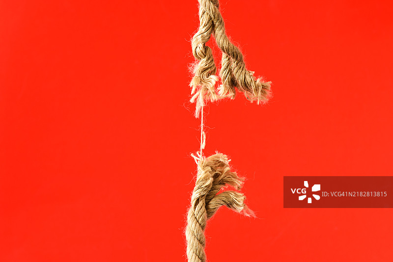 创意的破损绳索在红色背景上图片素材