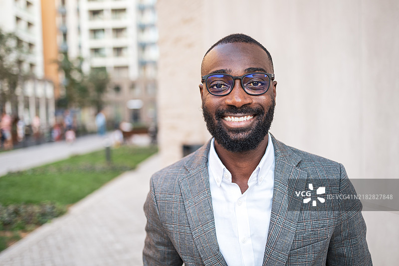 自信的商人在城市环境中微笑着。图片素材