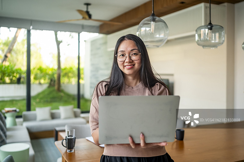 年轻女性在现代客厅用笔记本电脑远程工作图片素材