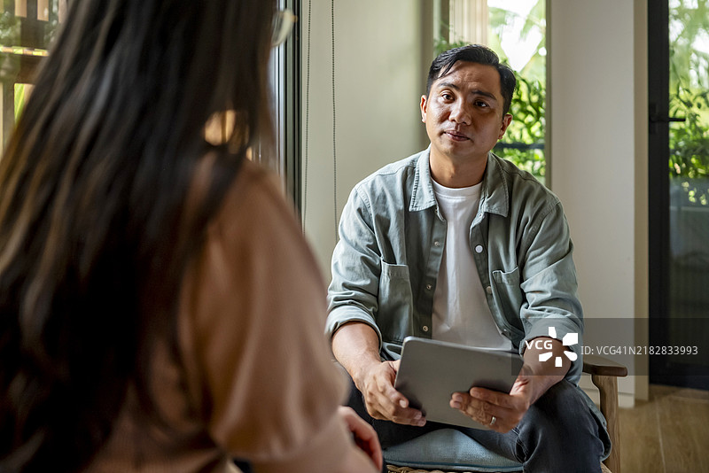 男子在室内手持平板电脑进行对话图片素材