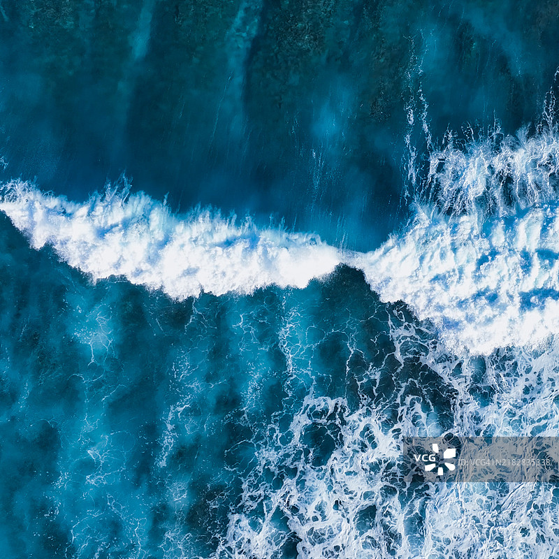 从上方俯瞰海浪拍打海岸线的无人机视角图片素材