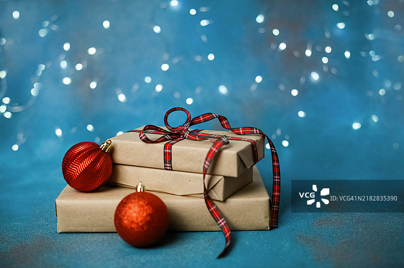 用红色格子丝带和装饰品包裹的圣诞礼物，背景为节日蓝色图片素材