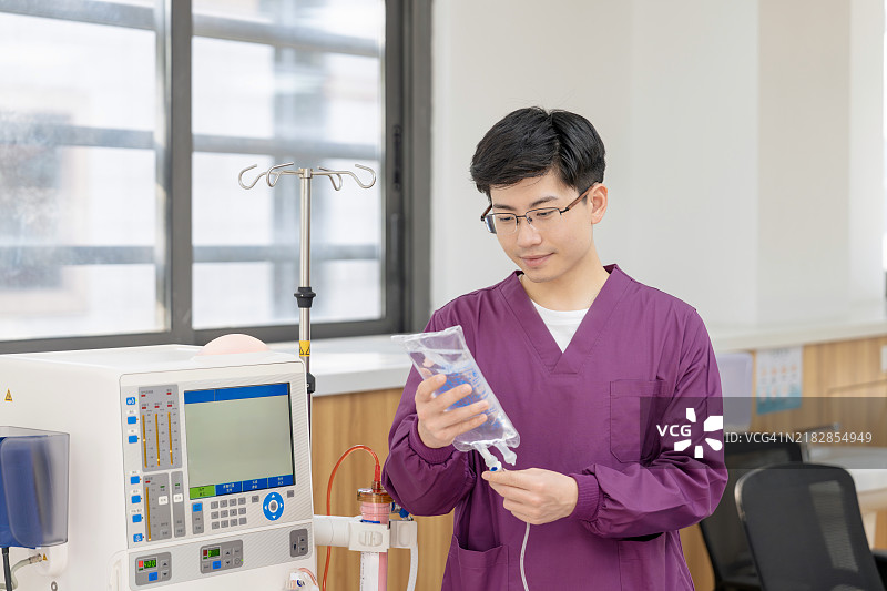 亚洲男性护士正在检查连续肾脏替代治疗设备、注射泵和血液透析机。图片素材